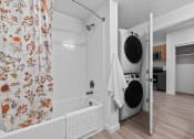 Thumbnail 9 of 20 - a laundry room with a washing machine and a tub and a shower curtain
