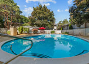 Thumbnail 2 of 15 - Curtis Apartments swimming pool with trees in the background and a fence
