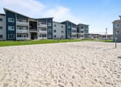 Thumbnail 11 of 21 - a beach with sand in front of an apartment building