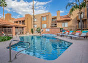 Thumbnail 2 of 13 - A pool surrounded by sun loungers and palm trees.