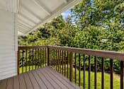 Thumbnail 6 of 23 - A wooden deck with a white house and trees in the background.