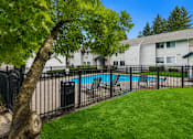 Thumbnail 19 of 23 - A tree with green leaves is in the foreground of a residential area with a pool and houses.