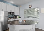 Thumbnail 21 of 34 - a kitchen with a granite counter top and a stainless steel refrigerator