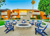 Thumbnail 18 of 24 - A fire pit is surrounded by blue chairs in a courtyard.