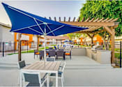 Thumbnail 20 of 24 - A patio with a table and chairs under a blue umbrella.