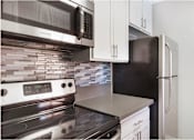 Thumbnail 2 of 24 - A modern kitchen with a stove, microwave, and refrigerator.