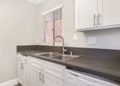 Thumbnail 10 of 24 - A kitchen with white cabinets and a stainless steel sink.
