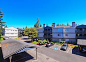Thumbnail 19 of 20 - A parking lot with cars and a building in the background.