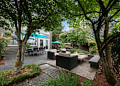 Thumbnail 15 of 20 - A modern outdoor seating area with a black sofa and table.