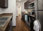 Thumbnail 5 of 20 - A kitchen with black appliances and brown cabinets.