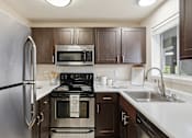 Thumbnail 3 of 20 - A kitchen with brown cabinets and a black stove top.