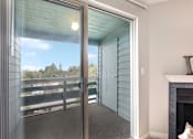Thumbnail 7 of 20 - A glass door leading to a balcony with a view of a parking lot and trees.