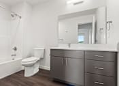 Thumbnail 30 of 34 - A modern bathroom with a white toilet, a white sink, and a large mirror.