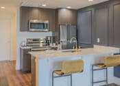 Thumbnail 12 of 35 - A modern kitchen with a white countertop and stainless steel appliances.