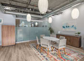 Thumbnail 16 of 29 - A room with a glass wall, wooden floors, and a white table with chairs.