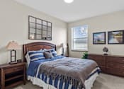 Thumbnail 5 of 24 - A bedroom with a bed, nightstand, and lamp.