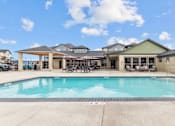 Thumbnail 12 of 24 - A large swimming pool in front of a building with a covered patio area.