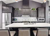 Thumbnail 14 of 24 - A modern kitchen with a large island and dark cabinets.