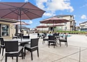 Thumbnail 20 of 24 - A patio with tables and chairs under umbrellas.