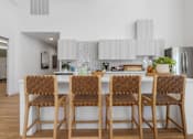 Thumbnail 15 of 34 - a kitchen with a long island with bar stools in front of a white counter