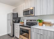 Thumbnail 20 of 34 - an apartment kitchen with stainless steel appliances and white cabinets