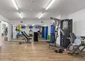 Thumbnail 30 of 34 - a gym with cardio equipment and weights on a wooden floor
