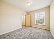 Thumbnail 14 of 47 - A room with a carpeted floor, a door, and a window.