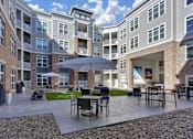 Thumbnail 5 of 23 - A patio with a table and chairs is surrounded by apartment buildings.