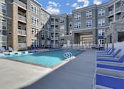 Thumbnail 11 of 23 - A large swimming pool is surrounded by apartment buildings.