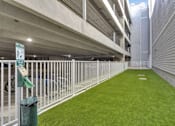 Thumbnail 6 of 23 - A parking garage with a green sign and a green trash can.