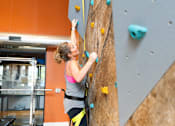 Thumbnail 34 of 35 - a woman climbing a rock wall in an indoor climbing gym