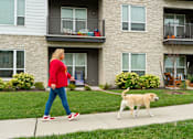 Thumbnail 35 of 35 - A woman walking her dog in front of a building.