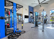 Thumbnail 15 of 43 - A gym with a variety of equipment including a weight rack, treadmill, and exercise bike.