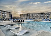 Thumbnail 18 of 43 - A swimming pool with a slide and loungers in front of apartment buildings.