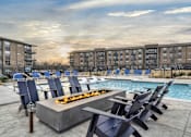 Thumbnail 20 of 43 - A fire pit sits in the middle of a pool surrounded by chairs.