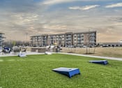 Thumbnail 21 of 43 - A grassy area with a blue object in the middle and apartment buildings in the background.