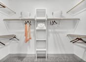 Thumbnail 40 of 43 - A white closet with a shelf and hangers.