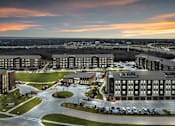 Thumbnail 43 of 43 - A large, modern building complex with a parking lot in front.