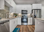 Thumbnail 32 of 53 - A modern kitchen with white cabinets and stainless steel appliances.