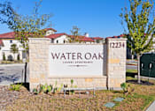 Thumbnail 74 of 92 - A sign for Water Oak Luxury Apartments is displayed in front of a building.
