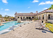 Thumbnail 25 of 92 - A pool area with sun loungers and a building in the background.