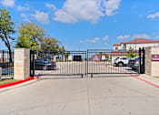 Thumbnail 77 of 92 - A black gate with a red stripe on the side blocks the entrance to a driveway.
