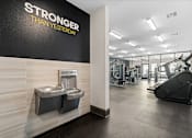 Thumbnail 32 of 92 - A gym with a wall that says "STRONGER THAN YESTERDAY" and a treadmill in the background.