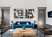Thumbnail 43 of 92 - A living room with a blue couch and a wooden coffee table.