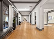 Thumbnail 44 of 92 - A long hallway with a bench and potted plants.
