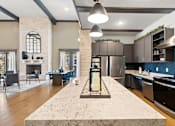 Thumbnail 64 of 92 - A modern kitchen with a stone fireplace and a marble island.