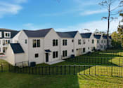 Thumbnail 5 of 63 - A row of white houses with black roofs and fences.