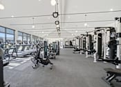 Thumbnail 1 of 63 - A spacious gym with various exercise equipment and a large window.