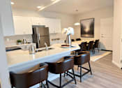 Thumbnail 3 of 10 - A kitchen with brown chairs and a white counter.