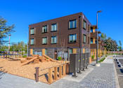 Thumbnail 12 of 13 - A modern building with a parking lot in front.